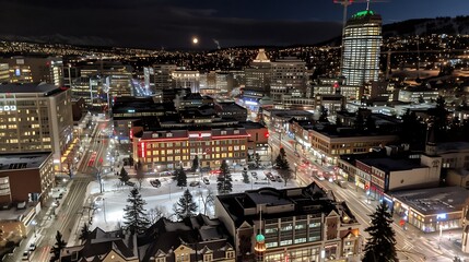 Obraz premium Panoramic view of a vibrant illuminated cityscape at night with soft snow cover