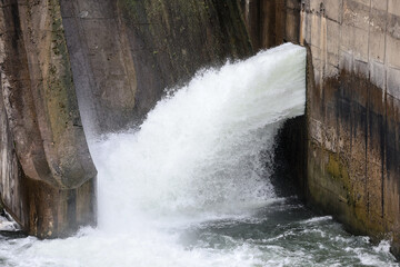 Overflow gate opened on a big concrete dam. Large volume of water flowing at high pressure.