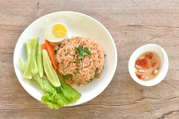 spicy fried rice with mashed salmon topping half boiled egg eat couple fresh vegetable on plate dressing slice chili and garlic fish sauce 