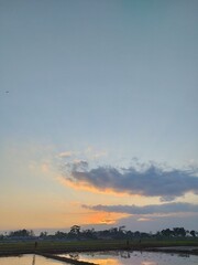 Beautiful sunset over rice fields with water reflection, perfect rural landscape for nature and agriculture themes.