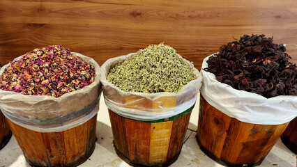 A row of three wooden barrels with aromatic dried herbs, spices and natural products at a traditional Middle Eastern market in Egypt. Tea and spices for sale at the market