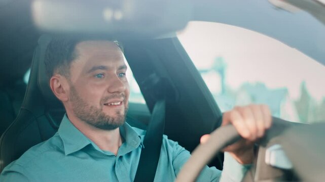 Handsome Caucasian male in blue shirt sitting behind wheel and smiling confidently. Holding steering wheel while pausing before drive. Feeling relaxed and ready for productive journey ahead.