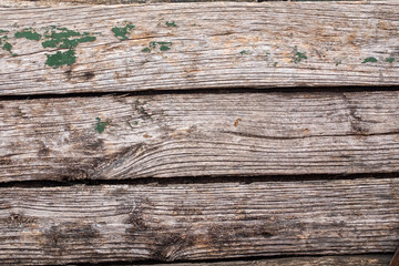 A straight-on close-up of a series of old, weathered wooden planks with prominent horizontal grain lines and small patches of peeling green paint. This image is a fantastic textural resource, perfect 
