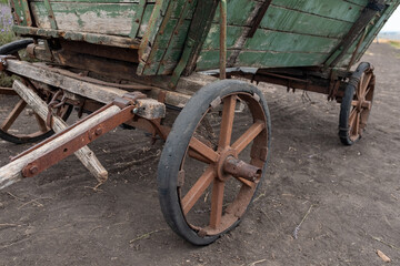 This image features the rusted, weathered wheels and part of a vintage wooden wagon, conveying a sense of history, decay, or rustic abandonment