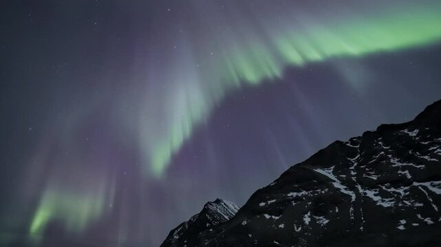 Auroras above snowy mountais in Norway, tilt and zoom up