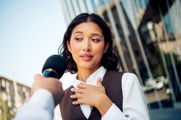 Beautiful professional businesswoman in formal attire being interviewed outdoors in a modern...