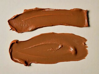Swatches of creamy brown paint or clay with smooth texture on light background
