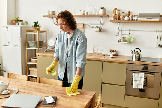 A handsome young man is busily tidying up his stylish home kitchen with focused attention