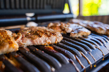 Pork steak being grilled on an electric grill, close-up