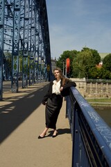 Confident young woman wearing a stylish black skirt, white ruffled blouse, and black blazer...