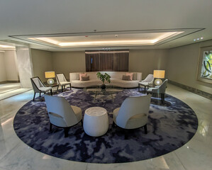 Elegant and minimalist hotel lobby interior with a circular seating arrangement, modern furniture,...
