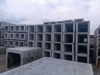 Organized stack of precast concrete U-ditch drainage channels at an outdoor construction material...