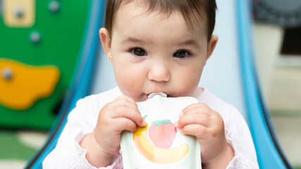 Baby eating fruit puree from food pouch outdoors