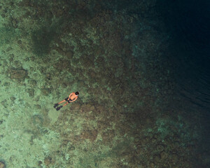 Top view bird's eye scuba divers in between the Vibrant Reefline and turquoise waters of Pescador...