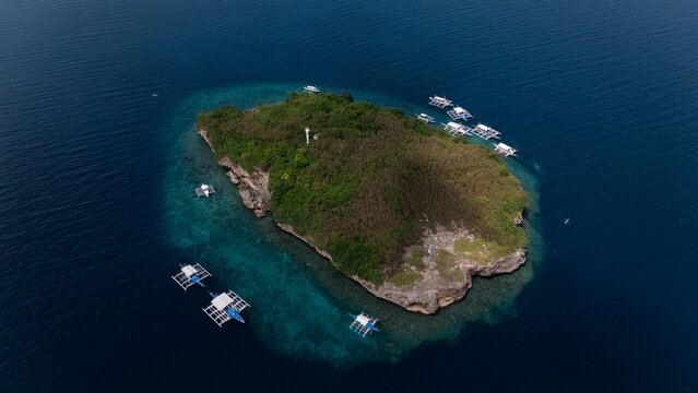 Full Aerial Island View of sunny paradise Pescador Island Surrounded by Bangkas boats and Turquoise vibrant Waters &ndash; Moalboal, Cebu, Philippines