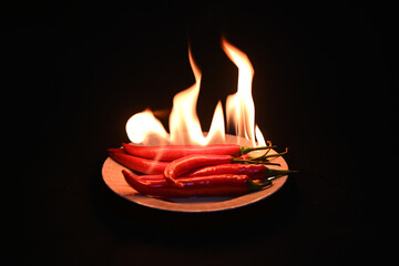 Red hot chili peppers with flame  on a dark background