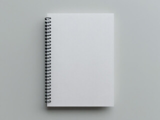 A blank white spiral notebook mockup with front cover up, placed on gray background, top-down view, minimal composition for stationery or education branding.