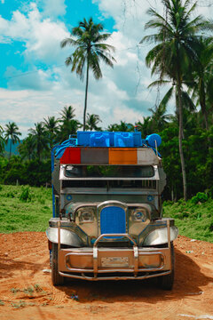 Jeepney jeep filipino colorful bus vehicle truck along tropical road with palm trees and sunny sky in Palawan, Philippines.