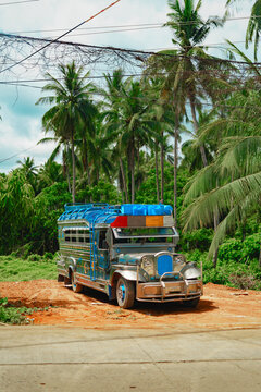 Jeepney jeep filipino colorful bus vehicle truck along tropical road with palm trees and sunny sky in Palawan, Philippines.