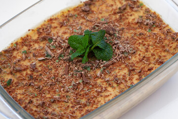 Traditional South African fridge tart in a glass dish with mint leaves and isolated on white