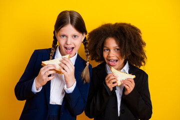 Two young girls in school uniforms enjoying sandwiches together, highlighting friendship and...