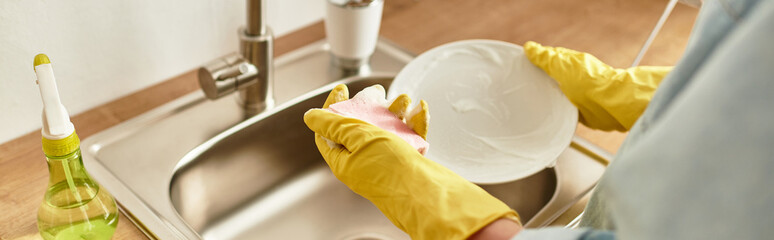 Handsome young man washing dishes at home while enjoying a moment of daily routine