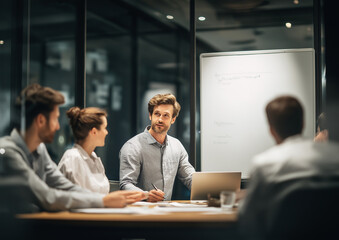 Naklejka premium Group of business people in an office sitting around a table, discussing ideas. A man holds a pen and points at a blank whiteboard, promoting teamwork, planning, and strategy