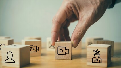 Hand selects video icon on wooden cube for online marketing strategy