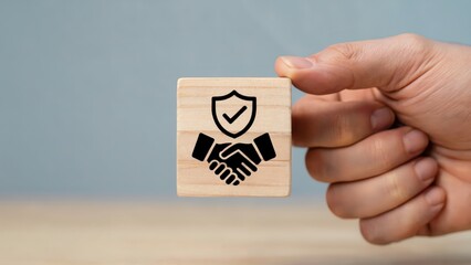 Secure handshake represented on a wooden block held by a hand