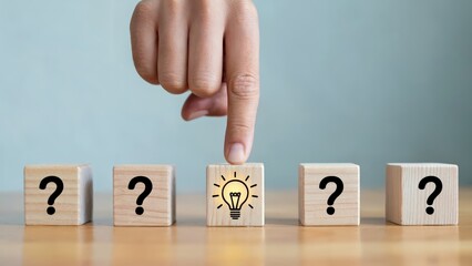 Concept of idea generation, hand pointing to lightbulb among question marks