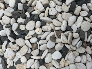Smooth white and dark gray pebbles, closely packed together, forming a textured surface.