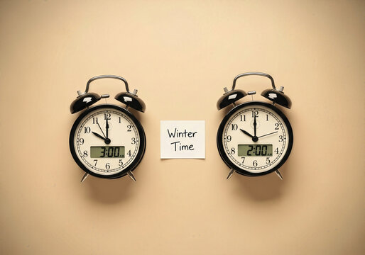 Daylight saving time ends concept with vintage alarm clocks and winter time note