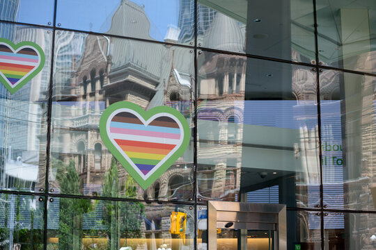 pride heart decals on the glass curtain wall of TD Canada Trust branch at 394 Bay St and Queen St W, Toronto (with reflection of Old City Hall)