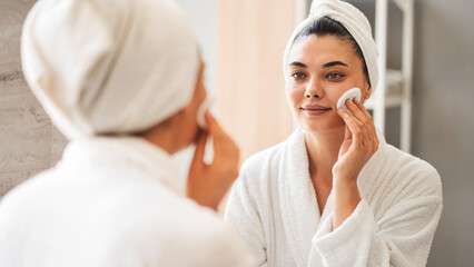 Woman cleaning skin with cotton pad