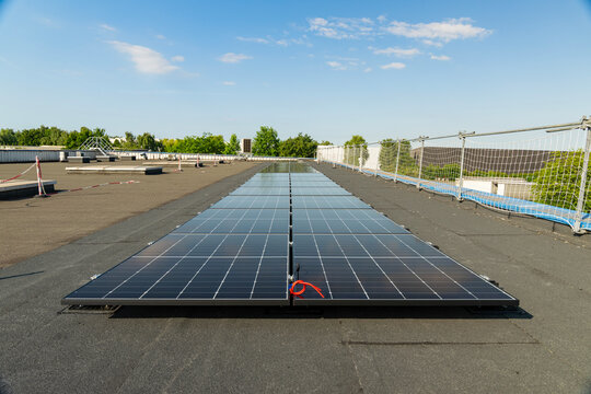 Vue sur des panneaux solaires install&eacute;s sur le toit plat d&rsquo;un b&acirc;timent industriel, capturant l&rsquo;&eacute;nergie solaire pour une production durable.