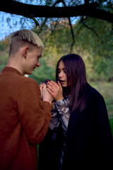 15-year-old teenage couple in love walks through the park on a cold autumn evening