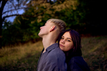 two 15-year-old teenagers in love play, hug, spend time together in an autumn park