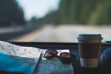 Travel Essentials: Map, Sunglasses, and Coffee on Dashboard