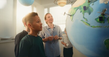 STEM Class: Female Teacher Explaining Renewable Energy Sources to Team of Smart Kids Using Earth...