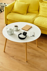 White coffee table with headphones and cup and kettle on it.