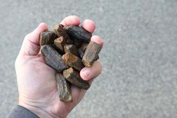 Andalusite held in partially closed hand. Mined to manufacture high temperature refractory, foundry steel and iron casting, ceramics, non slip or anti skit surfaces