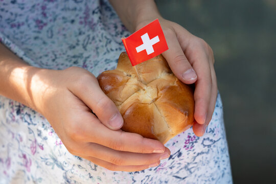Swiss traditional August bread bun with a swiss flag in child hands