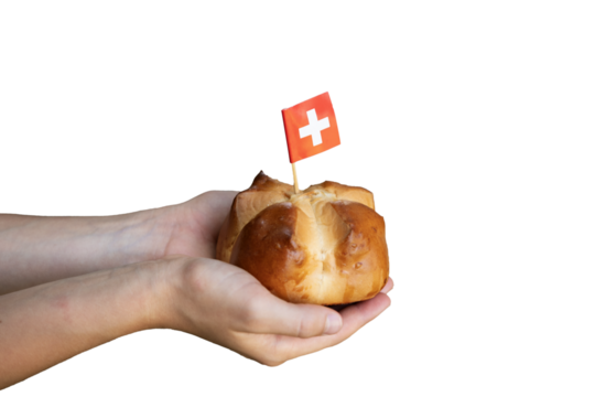 Child hands holding a national august bread bun with a swiss flag on isolated background