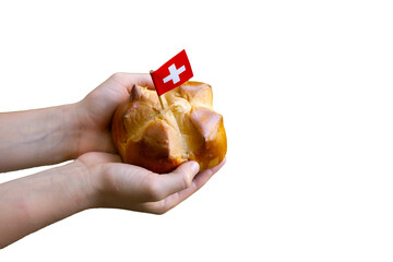 Child hands holding a national august bread bun with a swiss flag on isolated background with copy space