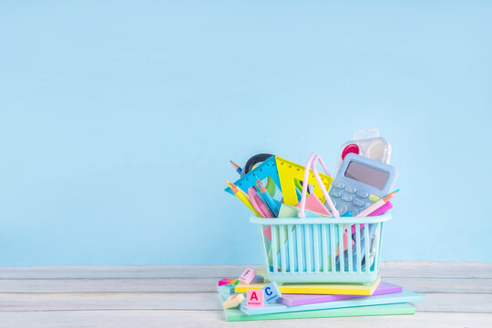 Back to school sale and shopping concept. Variety of school stationery in shopping basket pencils, paints, scissors, notebooks, calculator, school supplies, learning goods on colorful background 