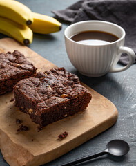 Vegetarian chocolate banana brownie on a wooden board  on a dark background