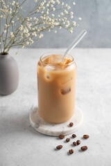 Ice latte coffee in a glass with milk on a marble board on a  light background with coffee beans