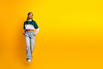 Naklejka premium Young stylish woman with braided hair and casual outfit posing against bright yellow background