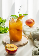 Ice tea with peach, mint in a glass on a white table near window with fresh fruits, herbs and shadows.