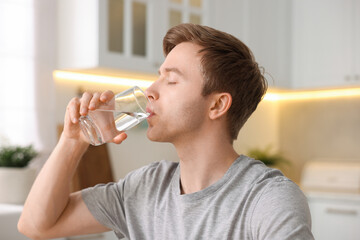 Man drinking water from glass in kitchen